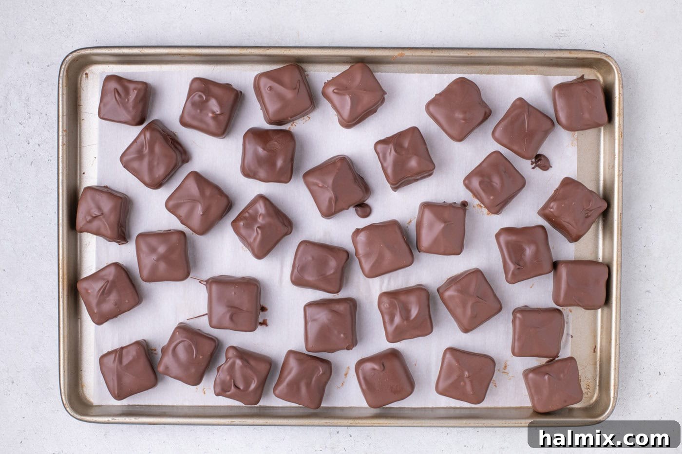 Creamy Cloud Bites 12 Finished chocolate-dipped Cool Whip Candies arranged on a baking sheet, ready to set.