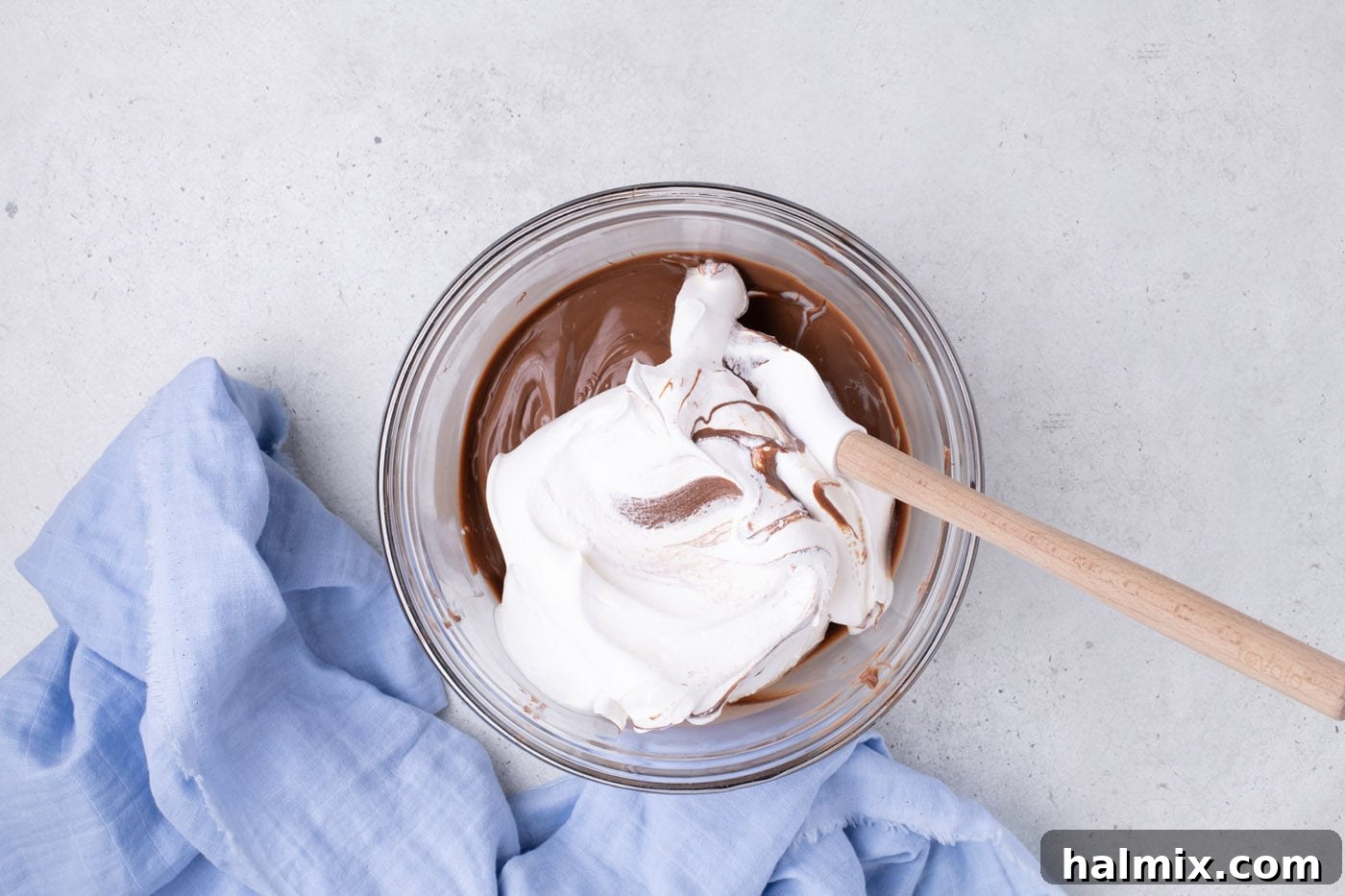 Creamy Cloud Bites 7 Cool Whip being gently folded into the whipped melted chocolate mixture in a bowl.