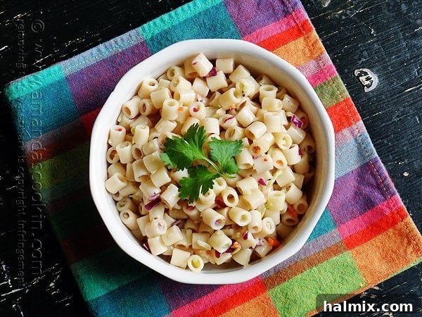 An overhead photo of pasta salad in a white bowl with parsley on top.