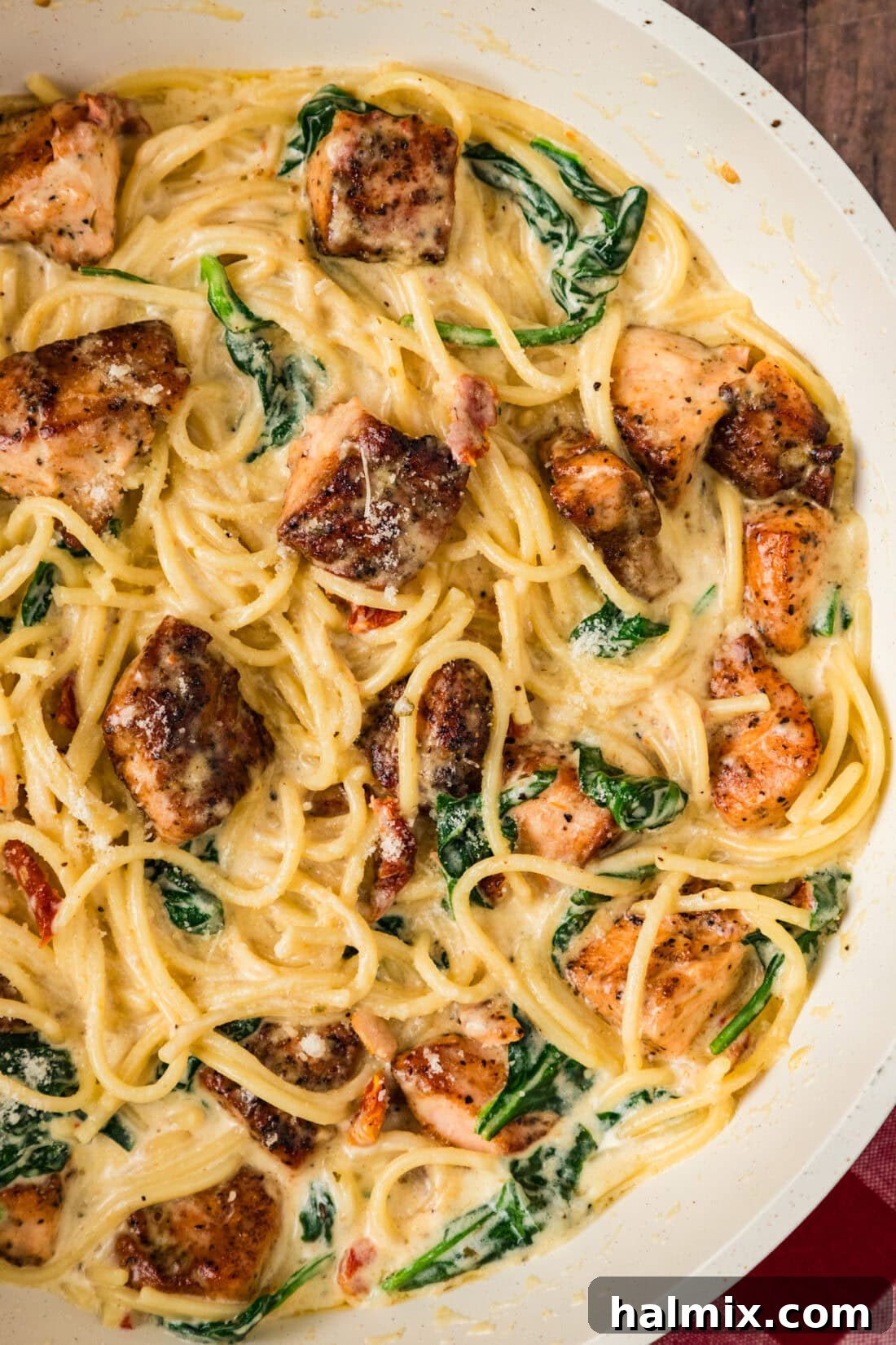 Close up photo of Creamy Salmon Pasta in a skillet, showcasing tender salmon, vibrant spinach, and rich sauce