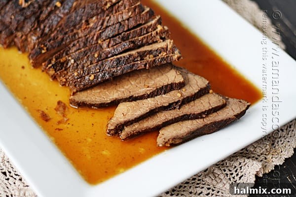 A close-up shot of tender slices of slow cooker beef roast coated in rich brandy sauce.
