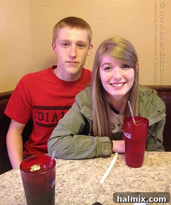 A young man and his girlfriend posing for a photo at a pizza restaurant.