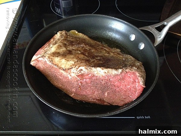 Beef roast searing in a hot skillet with olive oil until all sides are browned.
