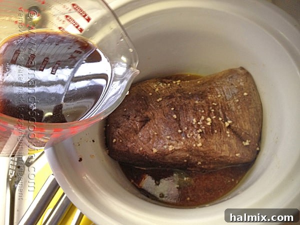 Pouring a rich liquid mixture over a beef roast in a slow cooker.