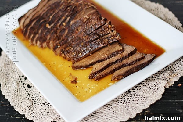 A close up of freshly sliced slow cooker roast, drizzled with the glossy brandy sauce.