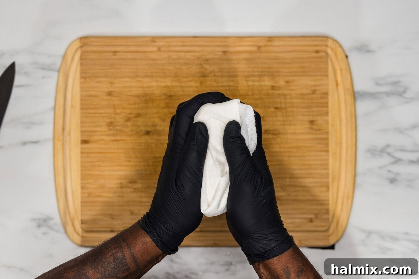 hands squeezing tofu in paper towels
