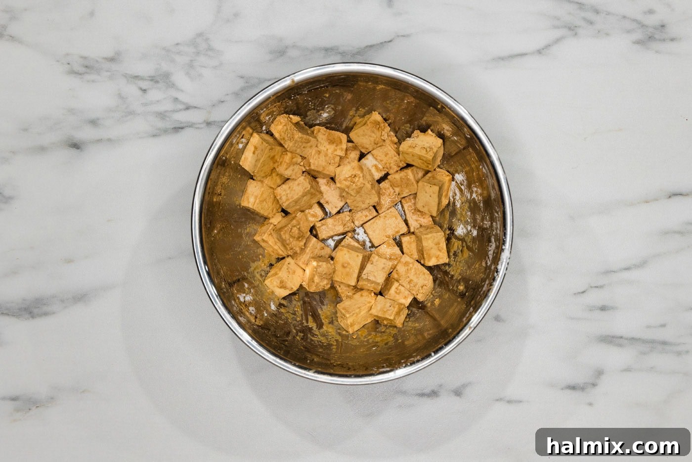 tofu cubes tossed in cornstarch and seasonings in a mixing bowl