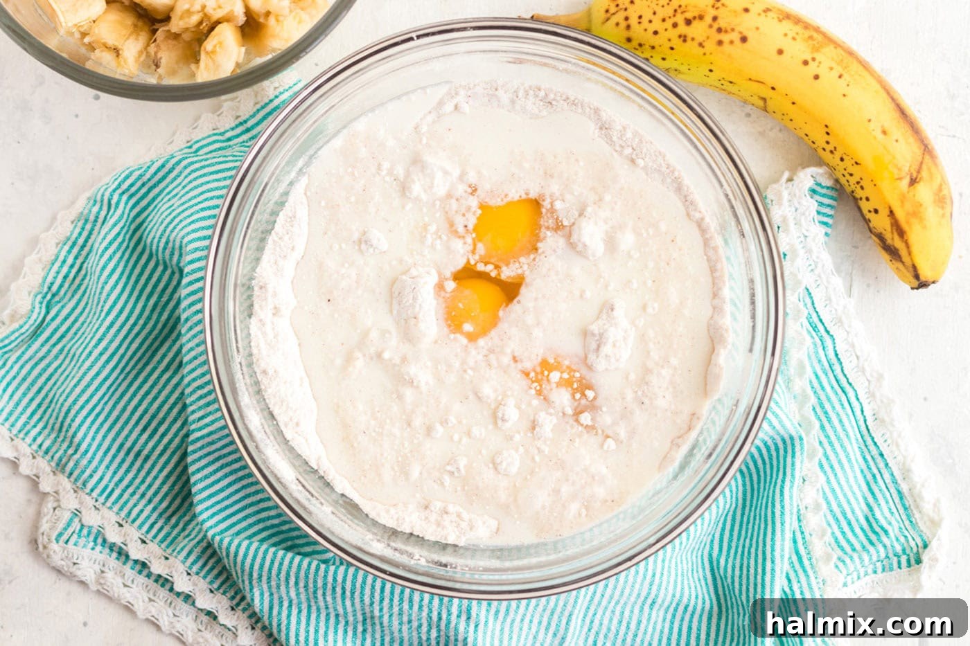 Simply Delicious Banana Cake 4 Cracked eggs in a bowl of cake mix and spices, preparing for the next step of mixing the cake batter.
