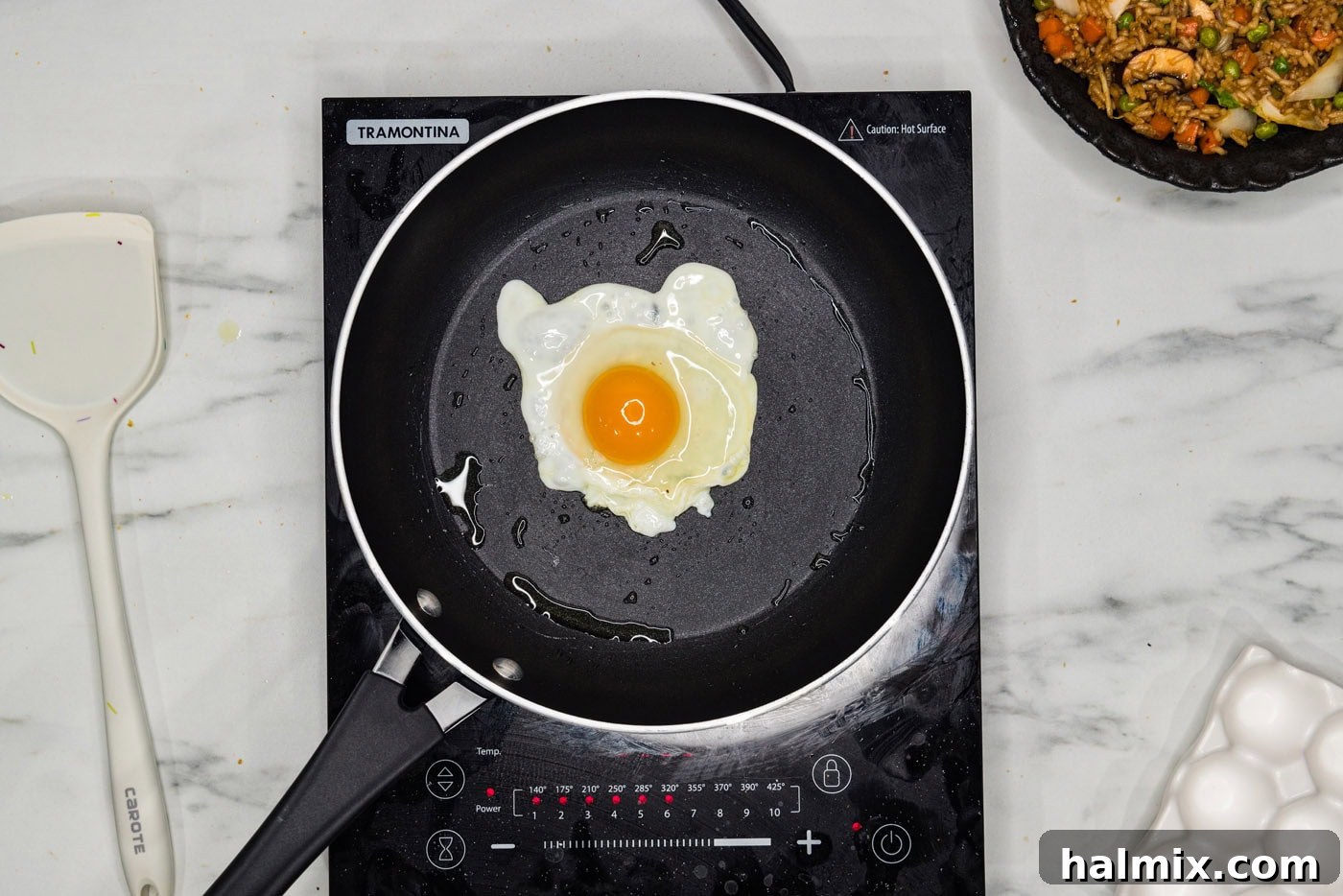A sunny side up egg frying in a hot skillet, ready to top the fried rice