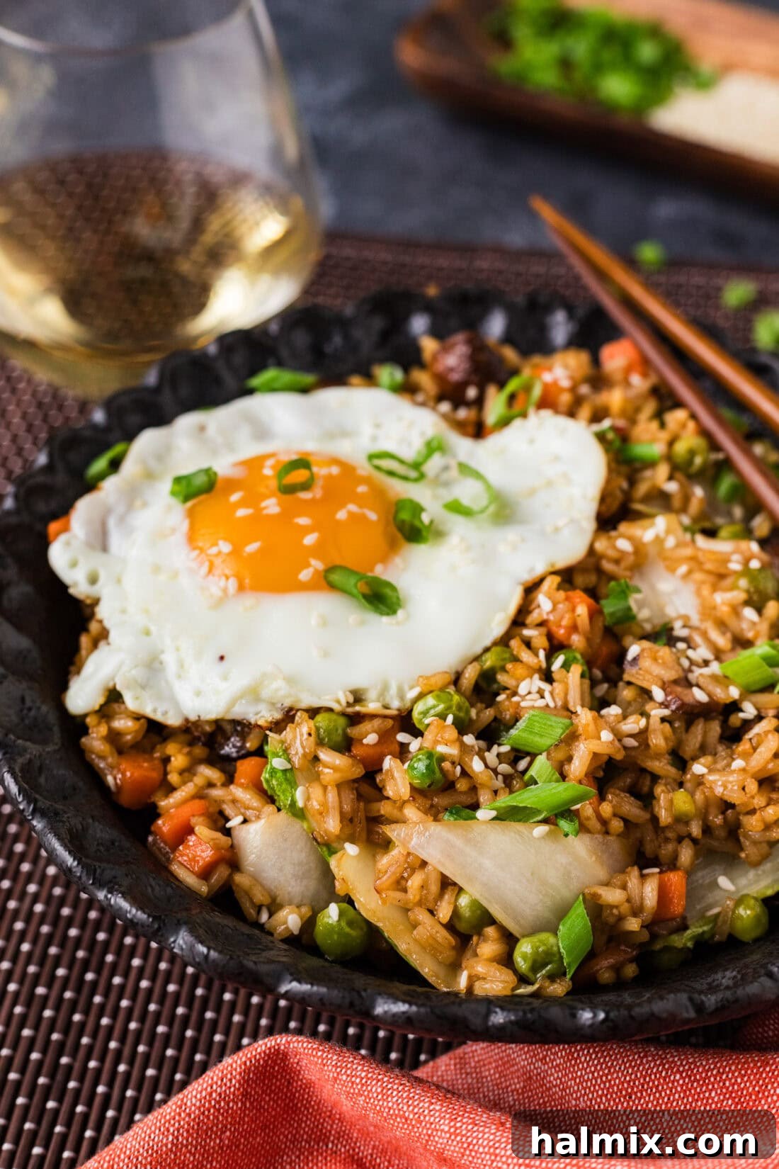 Close up side photo of a bowl of Korean Fried Rice with a fried egg and garnishes