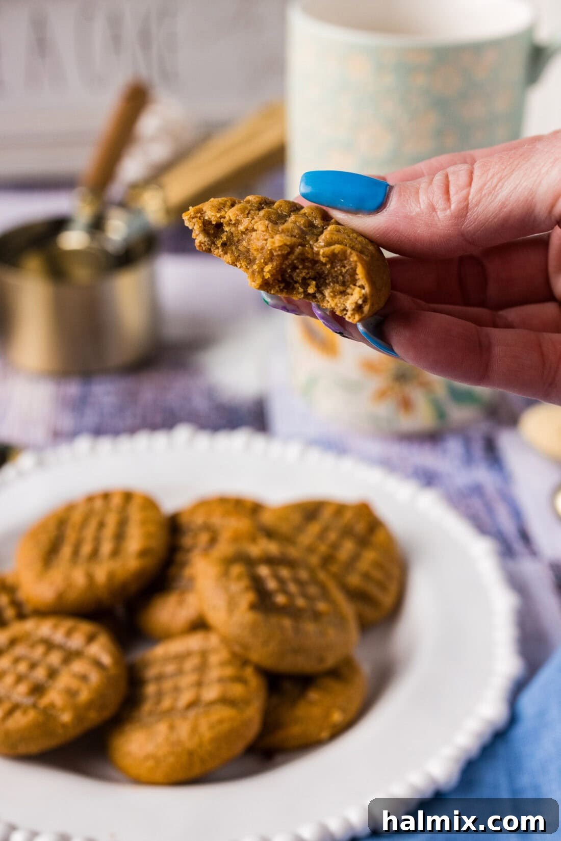 Hand holding up a Keto Peanut Butter Cookie with a bite removed, showcasing its chewy texture
