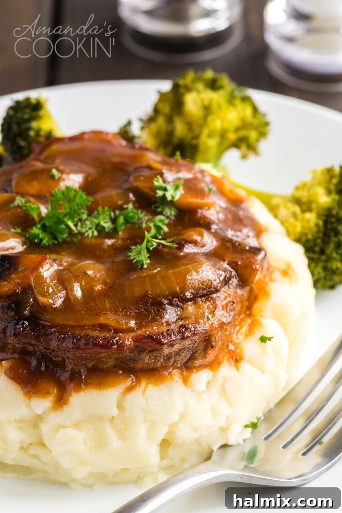 Swiss steak and gravy on a pile of mashed potatoes, ready to be served