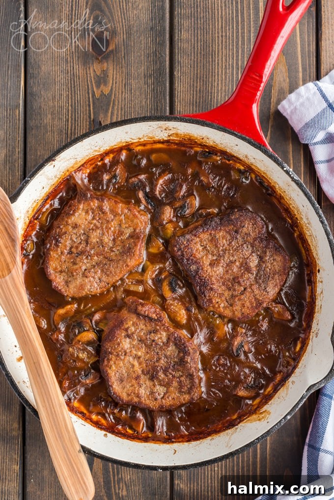 Baked swiss steak in a skillet, bubbling in its rich gravy after two hours in the oven