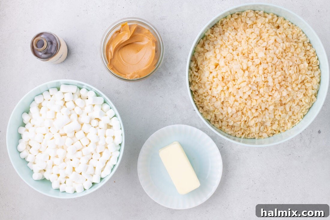 Peanut Butter Crunch Bars 4 Arrangement of all required ingredients for Peanut Butter Rice Krispie Treats: butter, creamy peanut butter, vanilla extract, mini marshmallows, and Rice Krispies cereal laid out on a clean surface.