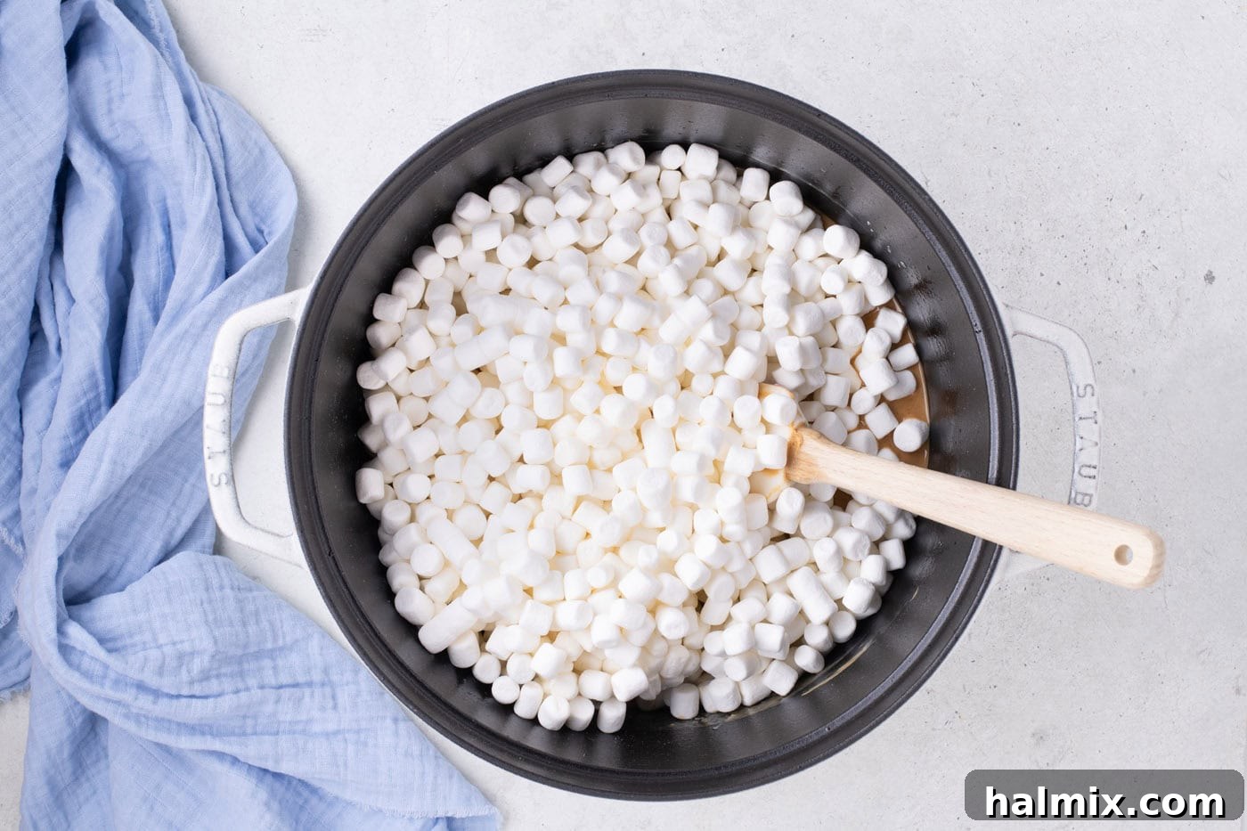 Peanut Butter Crunch Bars 7 Mini marshmallows melting into the peanut butter and butter mixture in a large pot, being stirred gently to create a sticky, cohesive base.