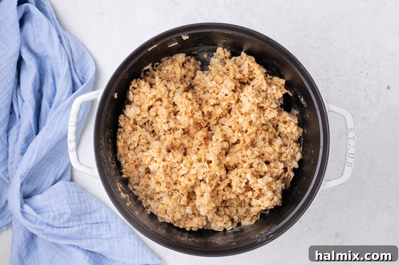 Peanut Butter Crunch Bars 8 Rice Krispies cereal being carefully folded into the warm, sticky peanut butter and marshmallow mixture in a large pot with a spatula.