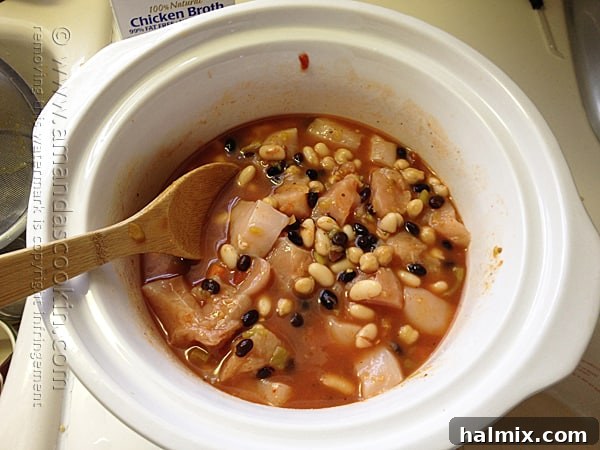Stir the cubed chicken into the slow cooker with the salsa and beans, ensuring even distribution before covering and cooking.