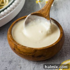 Zesty Lemon Cream Sauce 6 A bowl of vibrant Lemon Cream Sauce with a serving spoon, ready to be enjoyed.