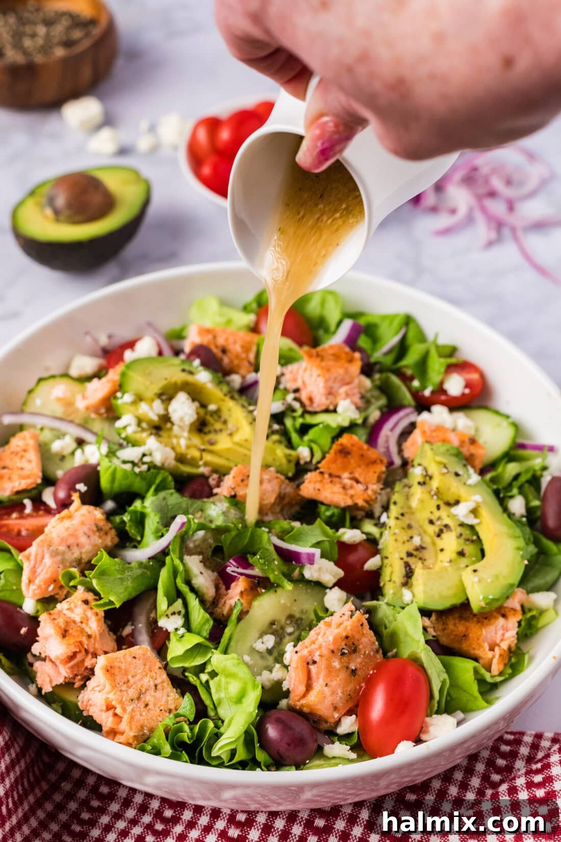 Vibrant Salmon Power Bowl 7 A hand drizzling vinaigrette dressing over a bowl of fresh Salmon Salad