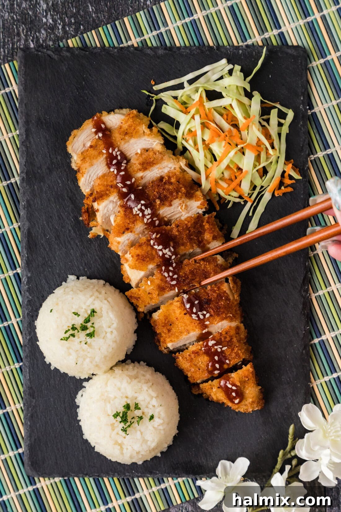 Golden Crispy Chicken Delight 3 Chopsticks reaching for a perfectly sliced piece of crispy Chicken Katsu, ready to be enjoyed.