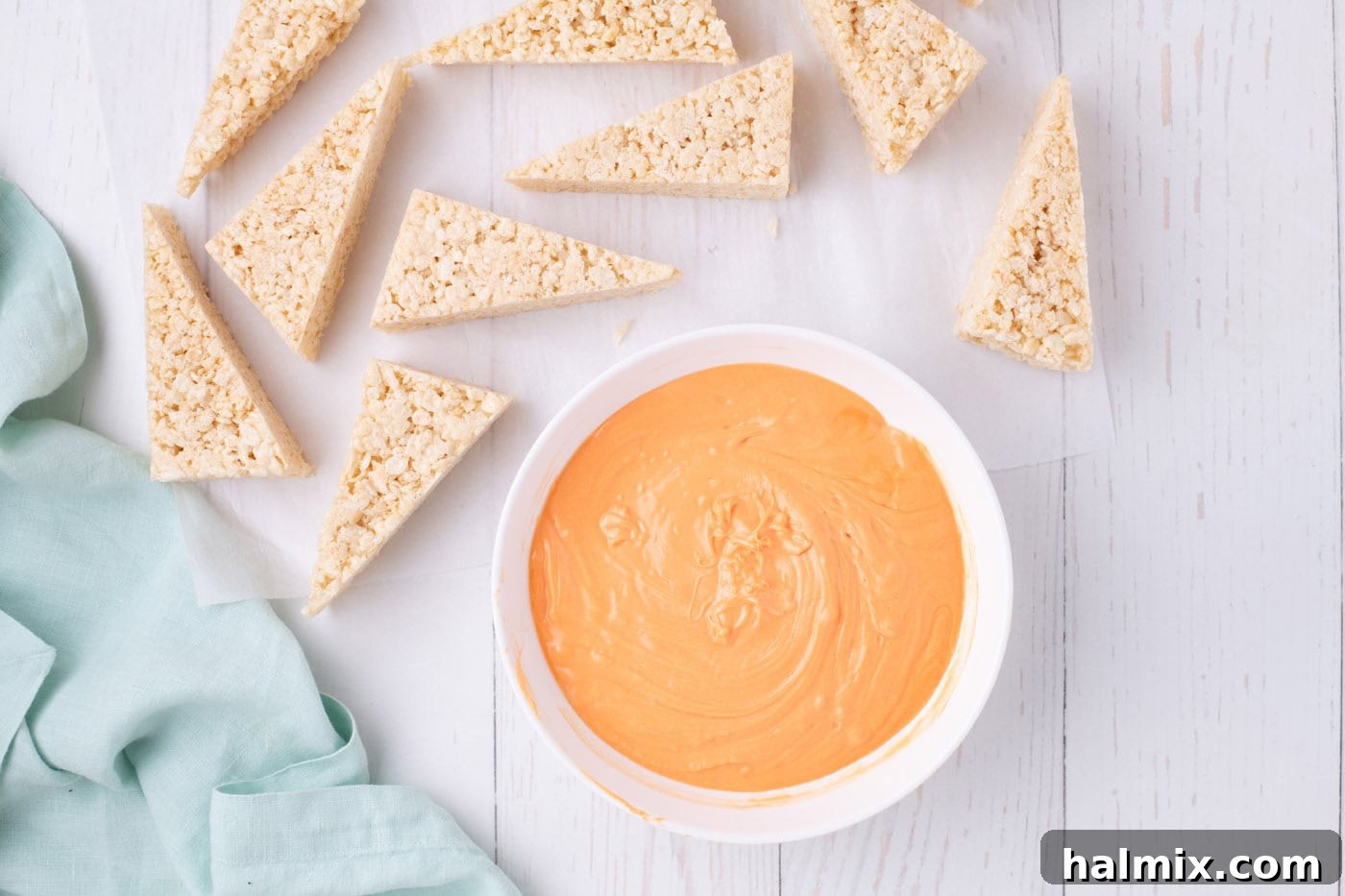 Carrot Cake Krispie Bites 8 Melted orange chocolate in a shallow bowl next to triangular Rice Krispie treats