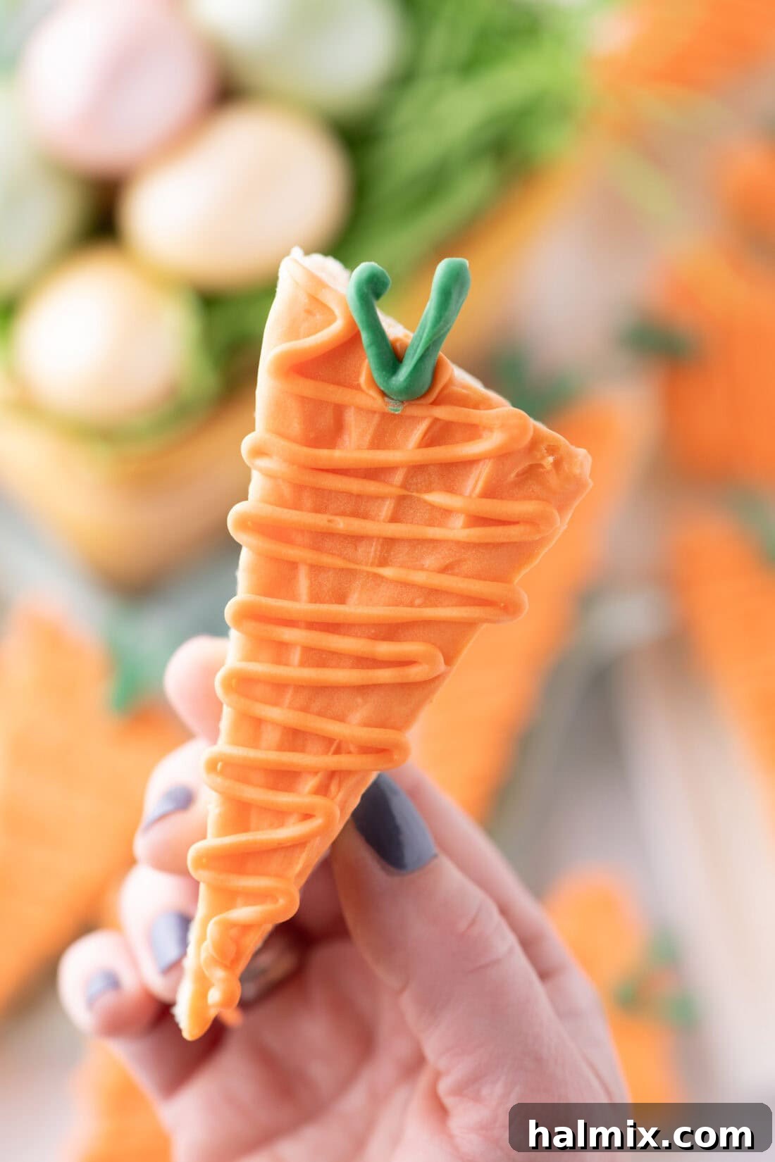 Carrot Cake Krispie Bites 3 A hand holding up a festive Carrot Rice Krispy Treat, showcasing its unique shape and decoration