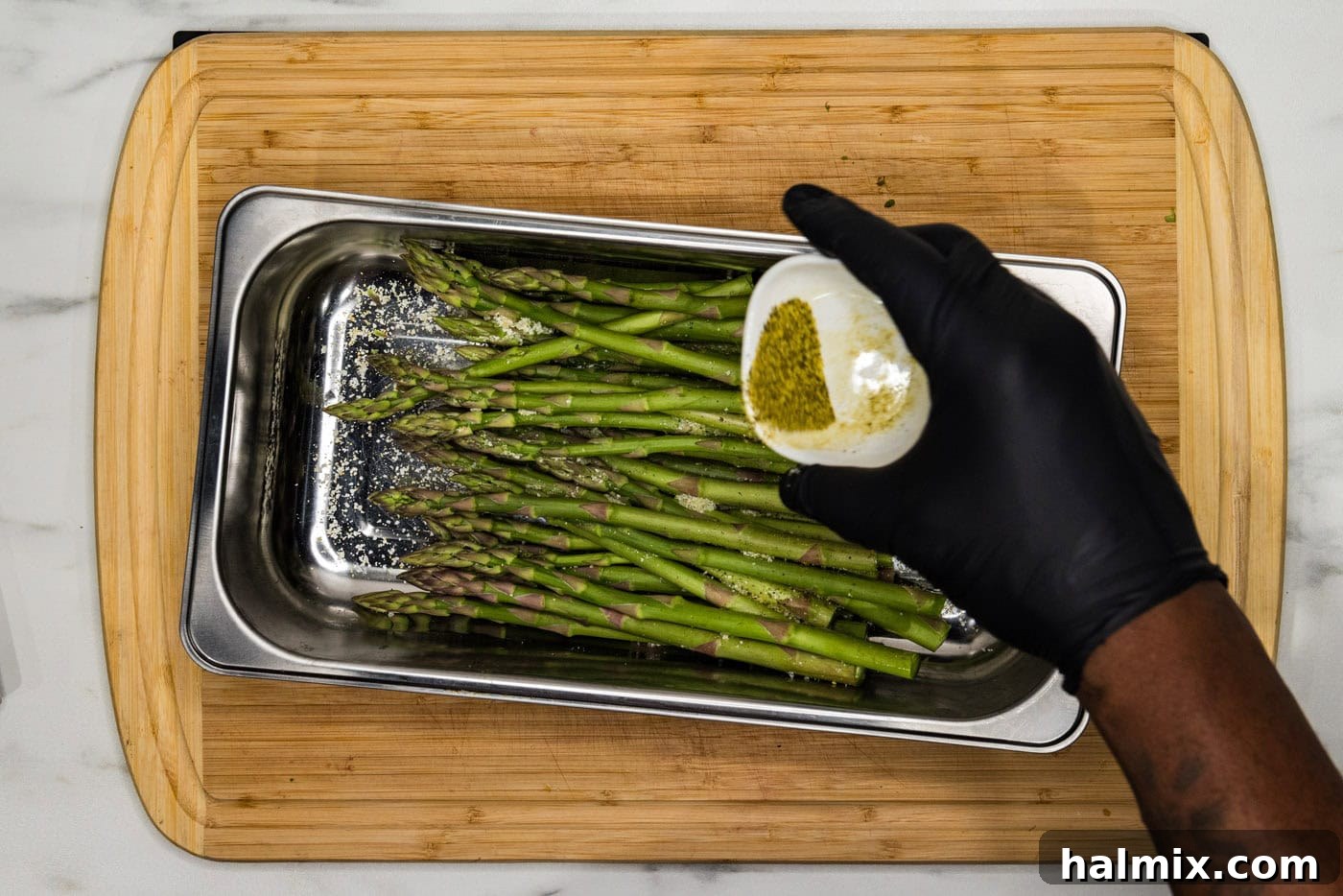 Bright Lemon Asparagus 6 hand seasoning asparagus in a pan with lemon pepper