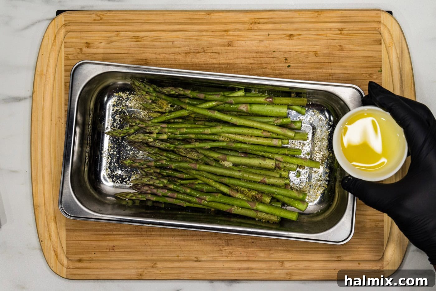 Bright Lemon Asparagus 7 hand holding olive oil in a bowl over asparagus for drizzling