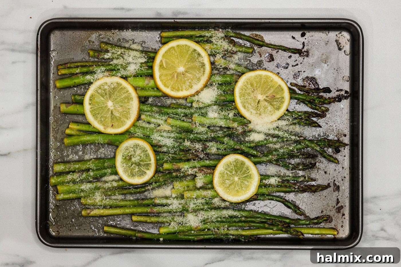 Bright Lemon Asparagus 9 roasted lemon asparagus on a baking pan with melted parmesan cheese, fresh out of the oven