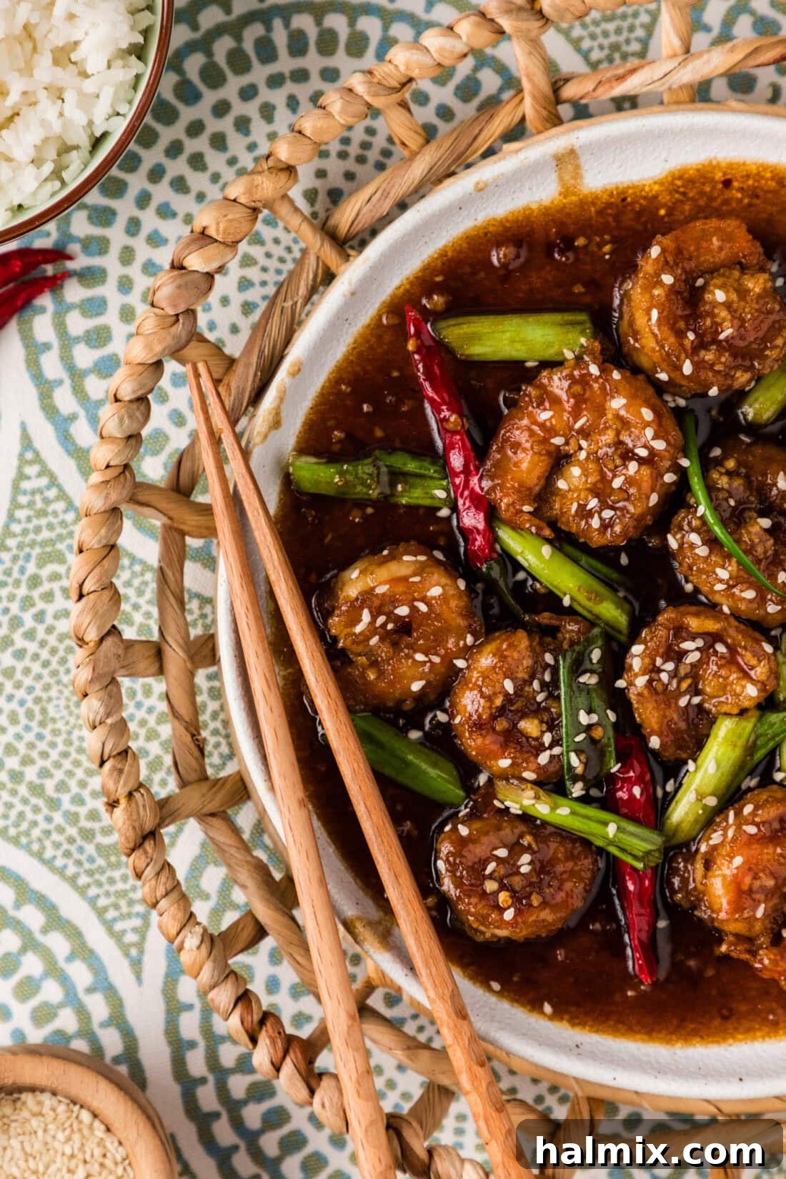 Close up photo of half of a plate of Mongolian Shrimp, garnished with green onions and sesame seeds.