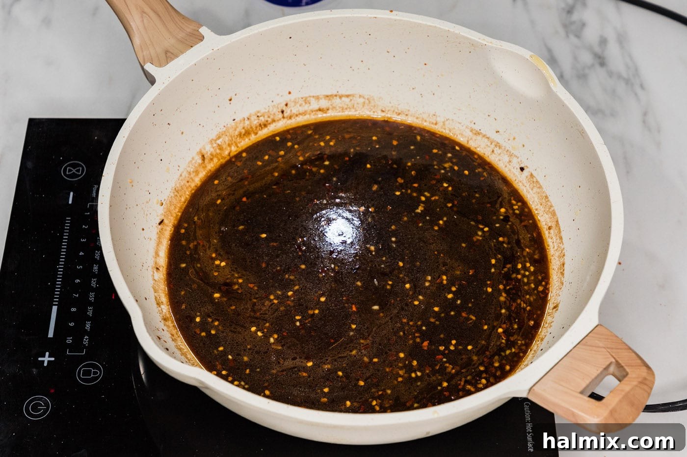 Mongolian sauce bubbling and thickening in a skillet.