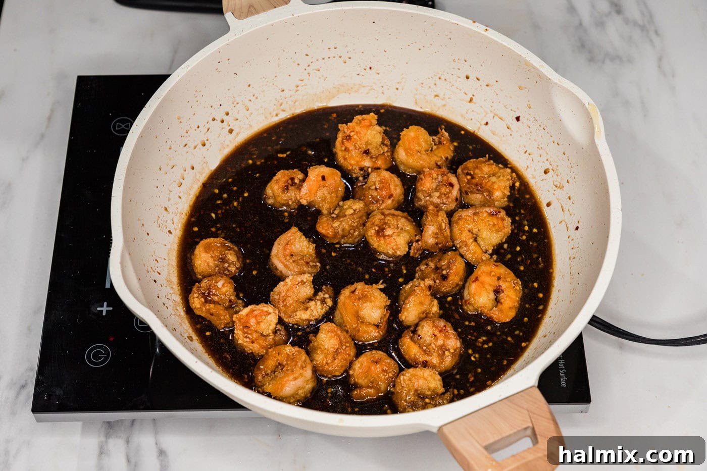 Breaded shrimp tossed in the Mongolian sauce in a skillet.