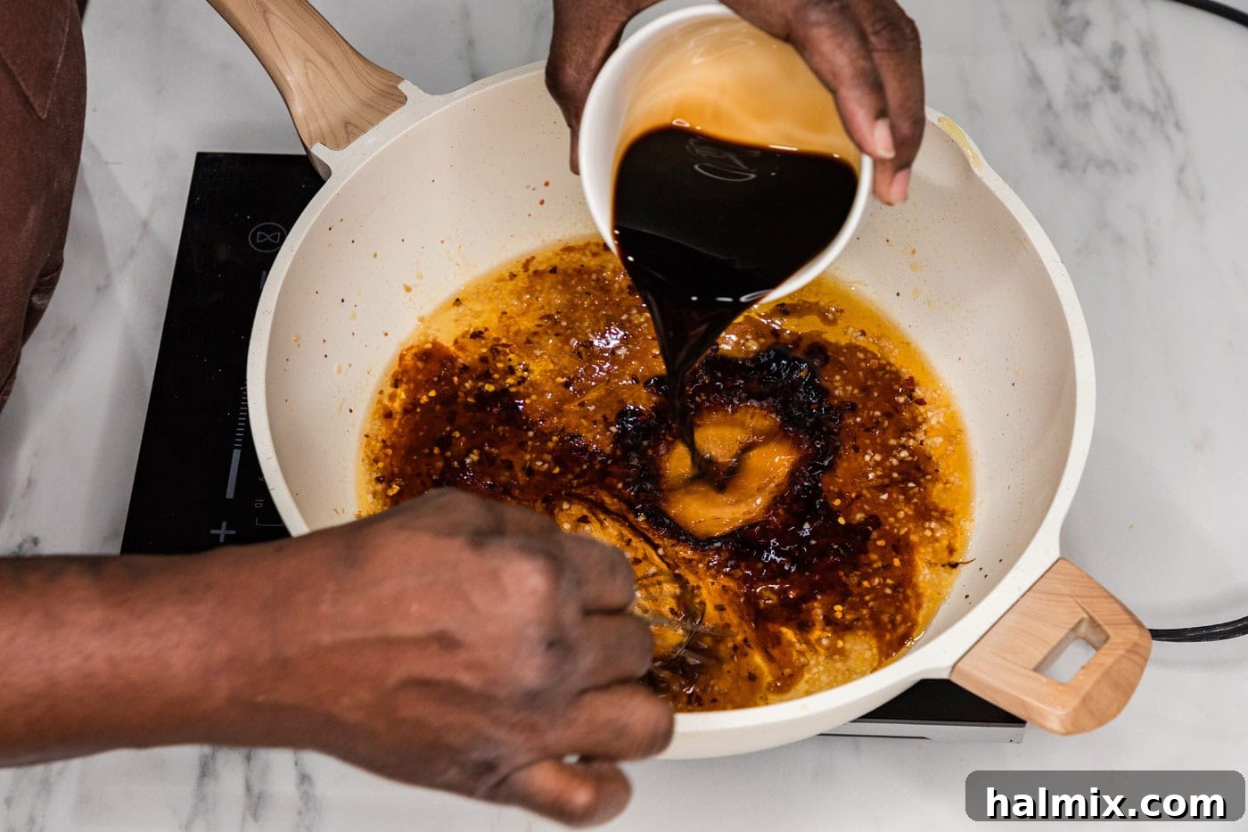 Whisking oyster sauce and other ingredients into the sauce in a skillet.