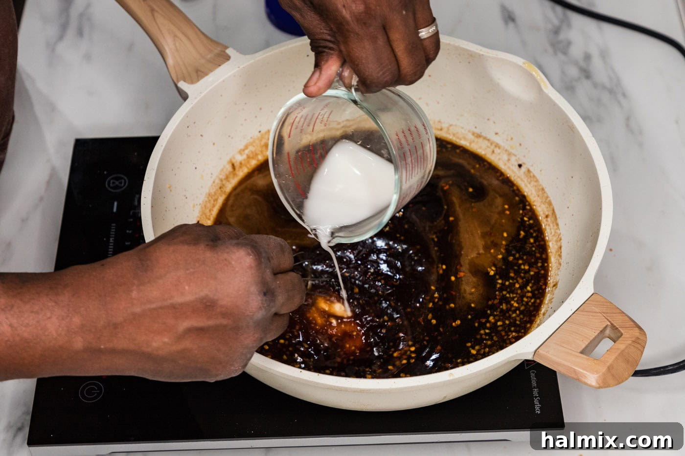 Adding a cornstarch slurry to the Mongolian sauce in a skillet to thicken it.