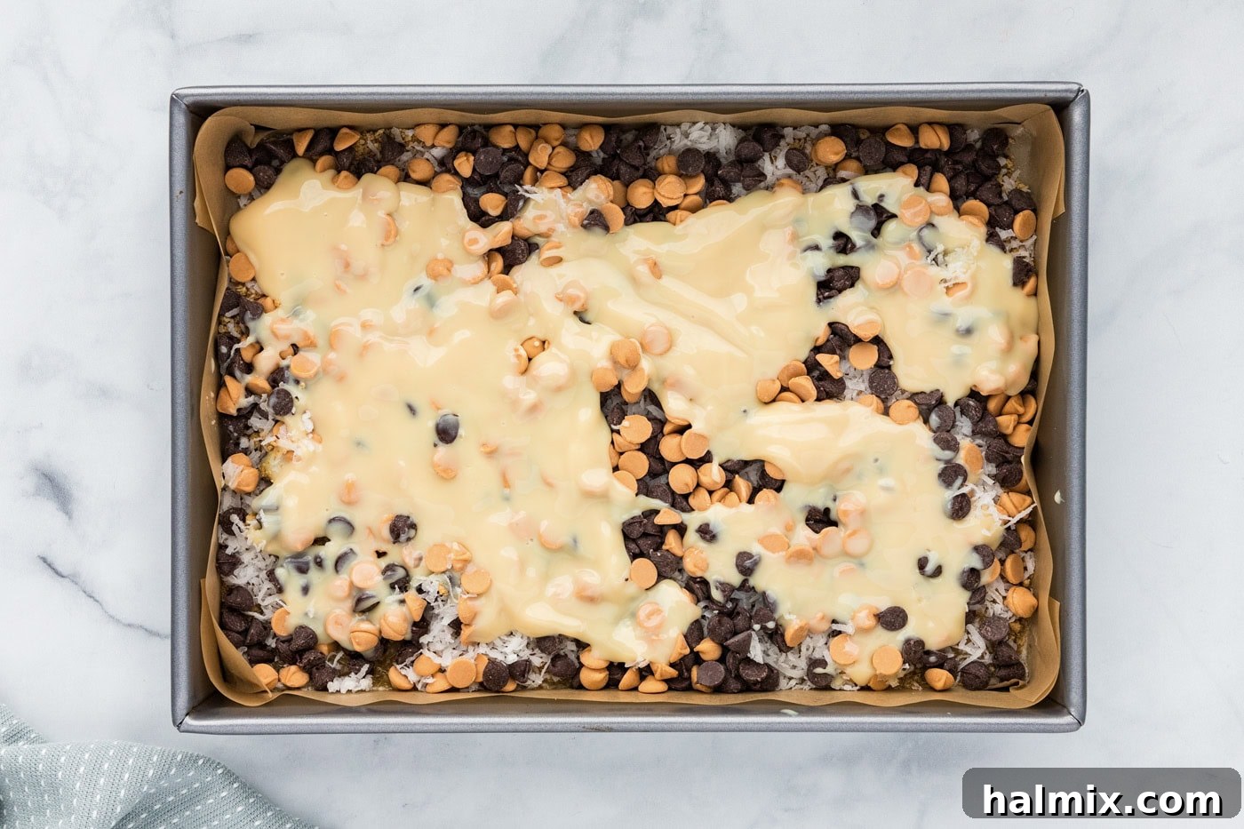 Sweetened condensed milk poured over the chocolate chip layer.