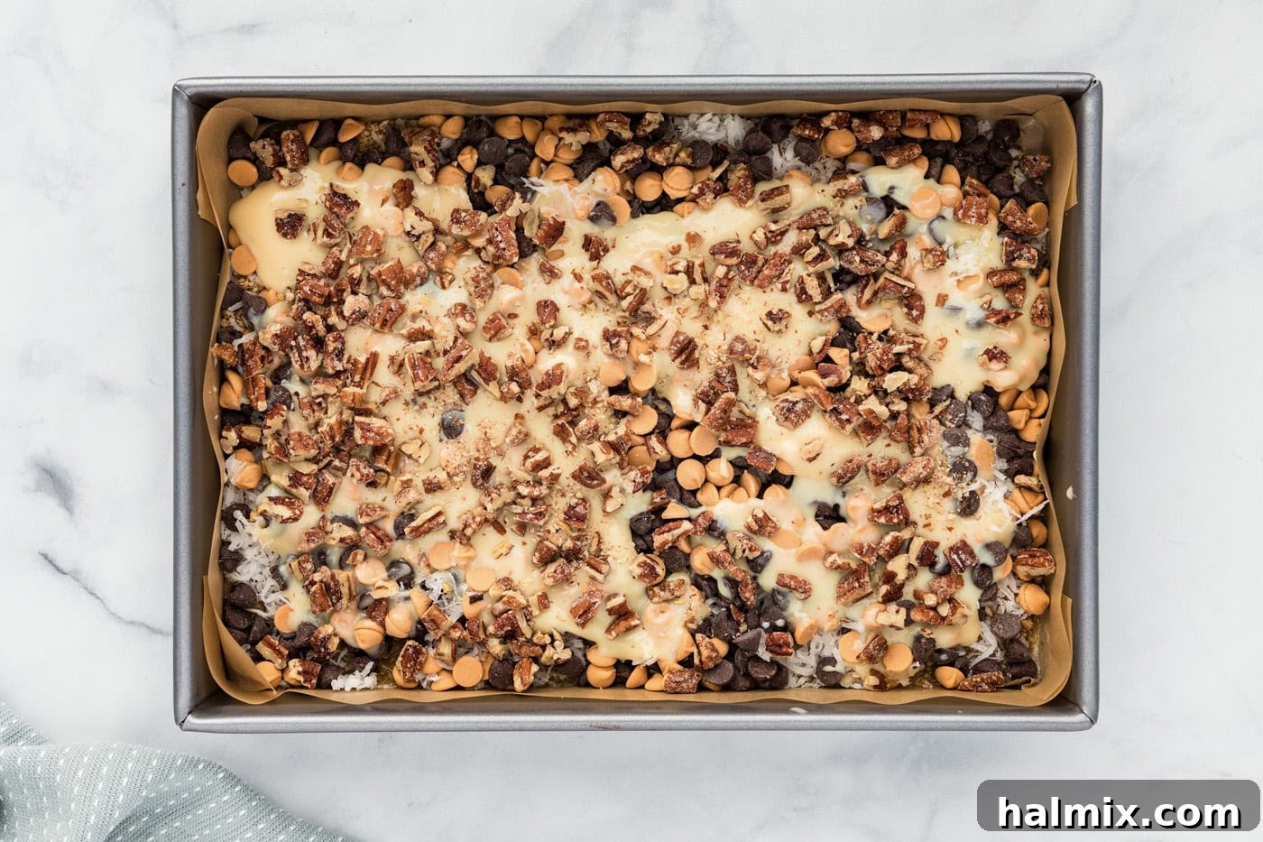 Chopped pecans sprinkled over the magic bars in a baking dish.