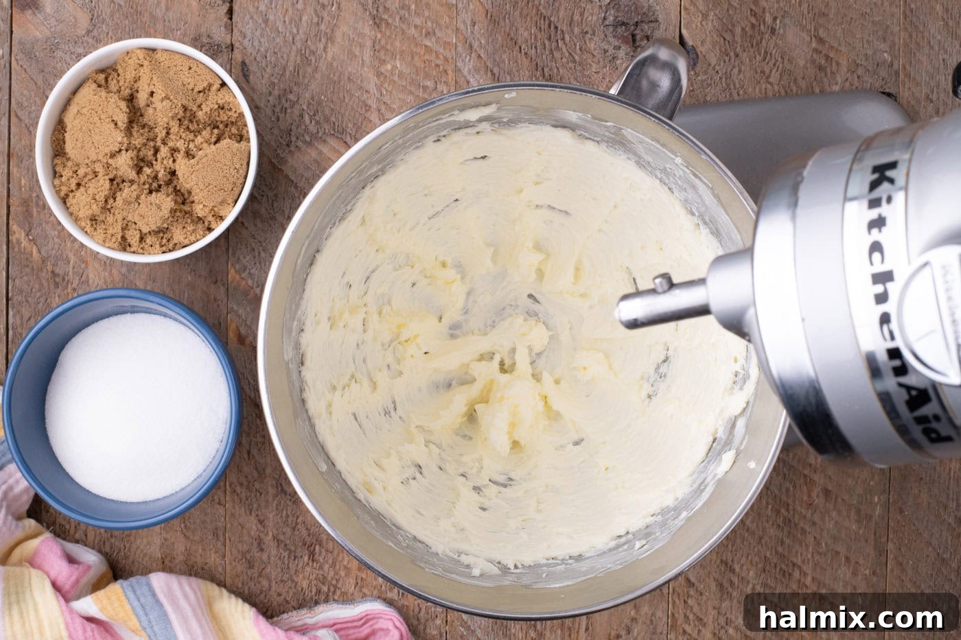 Room temperature butter being beaten until light and fluffy in a stand mixer bowl.