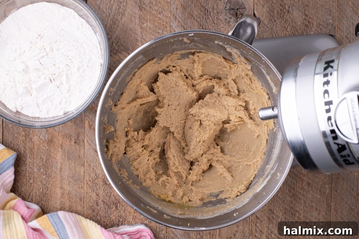 Eggs and vanilla extract being added to the butter and sugar mixture in a stand mixer.