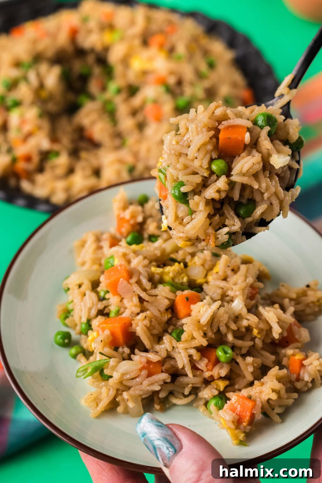 Spoonful of Vegetable Fried Rice being served onto a plate, highlighting its fresh ingredients