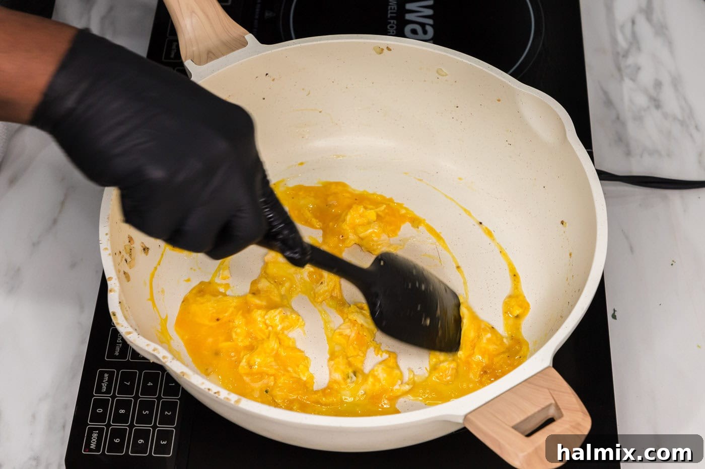 Scrambling eggs in a skillet with a rubber spatula until fluffy