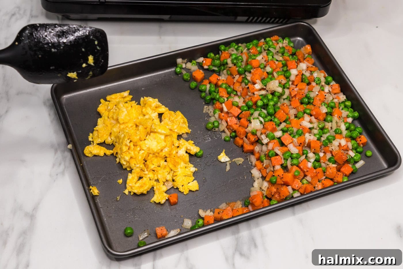 Scrambled eggs and stir-fried vegetables on a pan, awaiting the rice