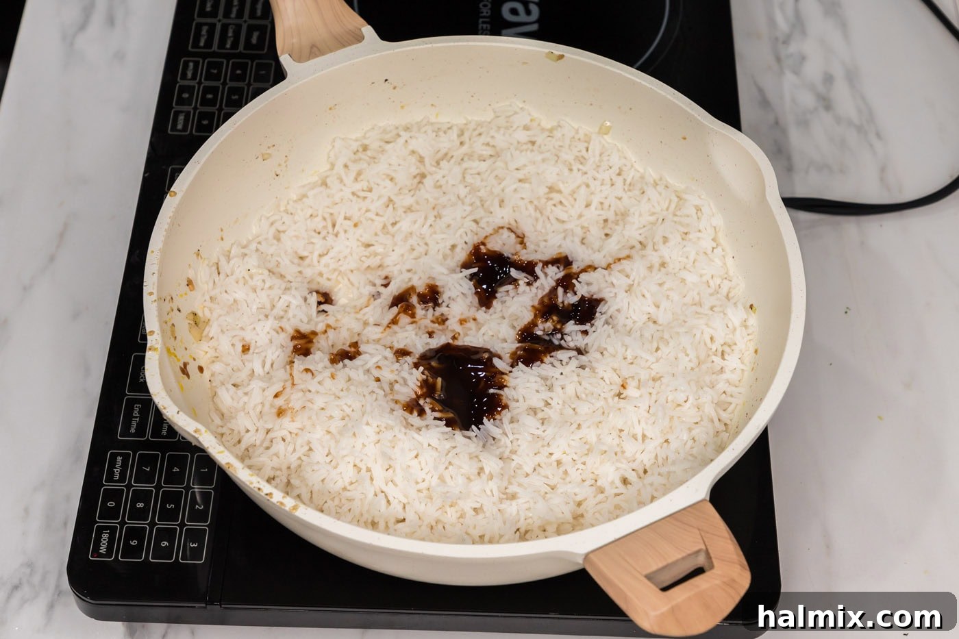 Soy sauce and oyster sauce added to a skillet with chilled rice, ready to be combined
