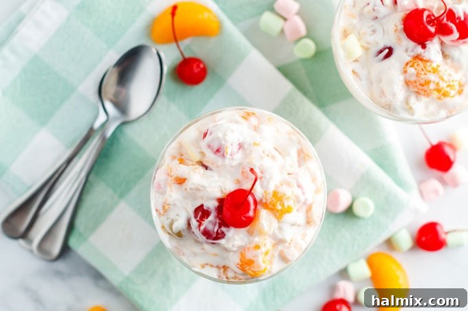 An inviting overhead view of a fluffy Ambrosia Salad dessert in a clear bowl, showing its colorful layers and textures.