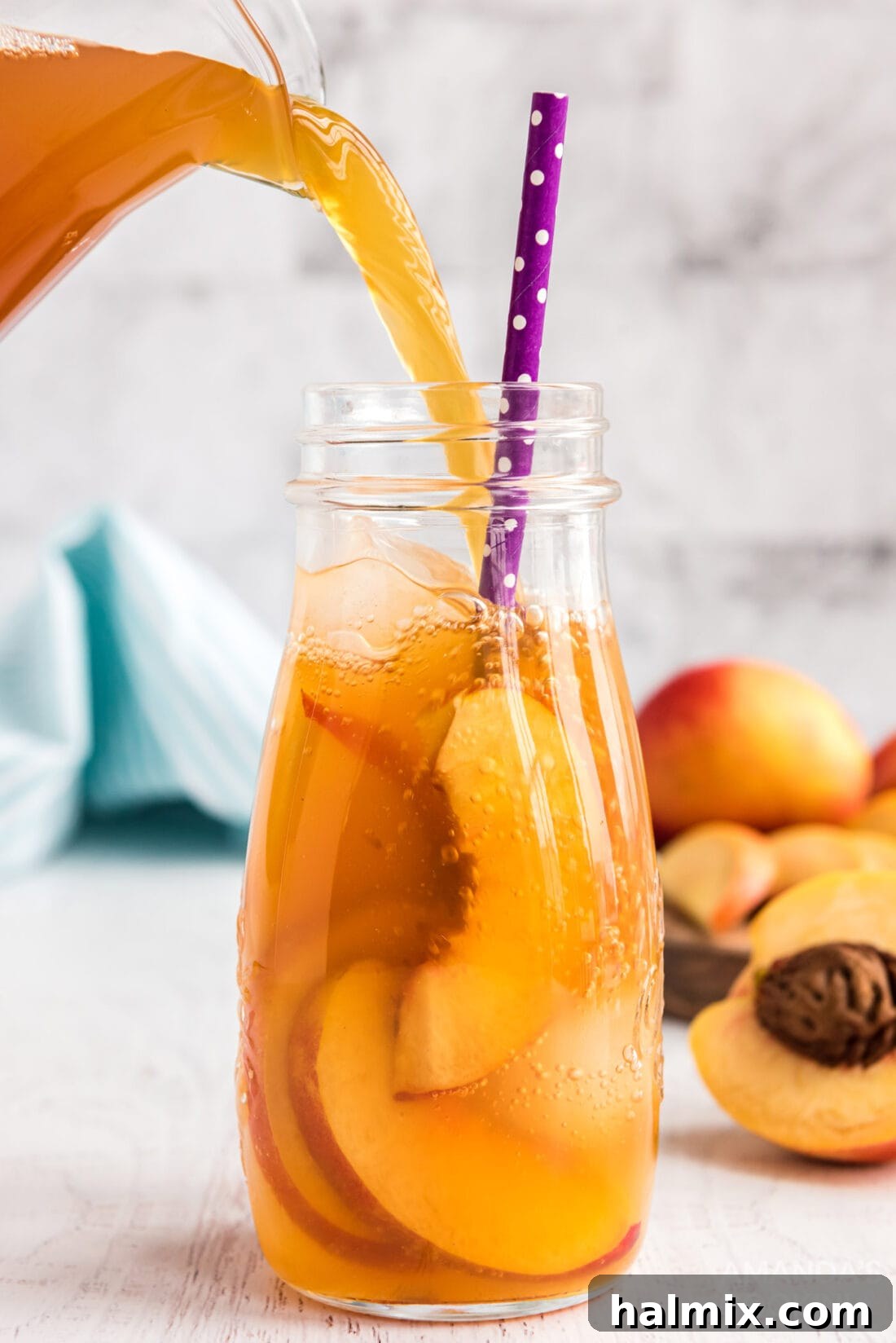 Sun-Kissed Peach Tea 2 Pouring refreshing peach iced tea into a glass with ice and peach slices.