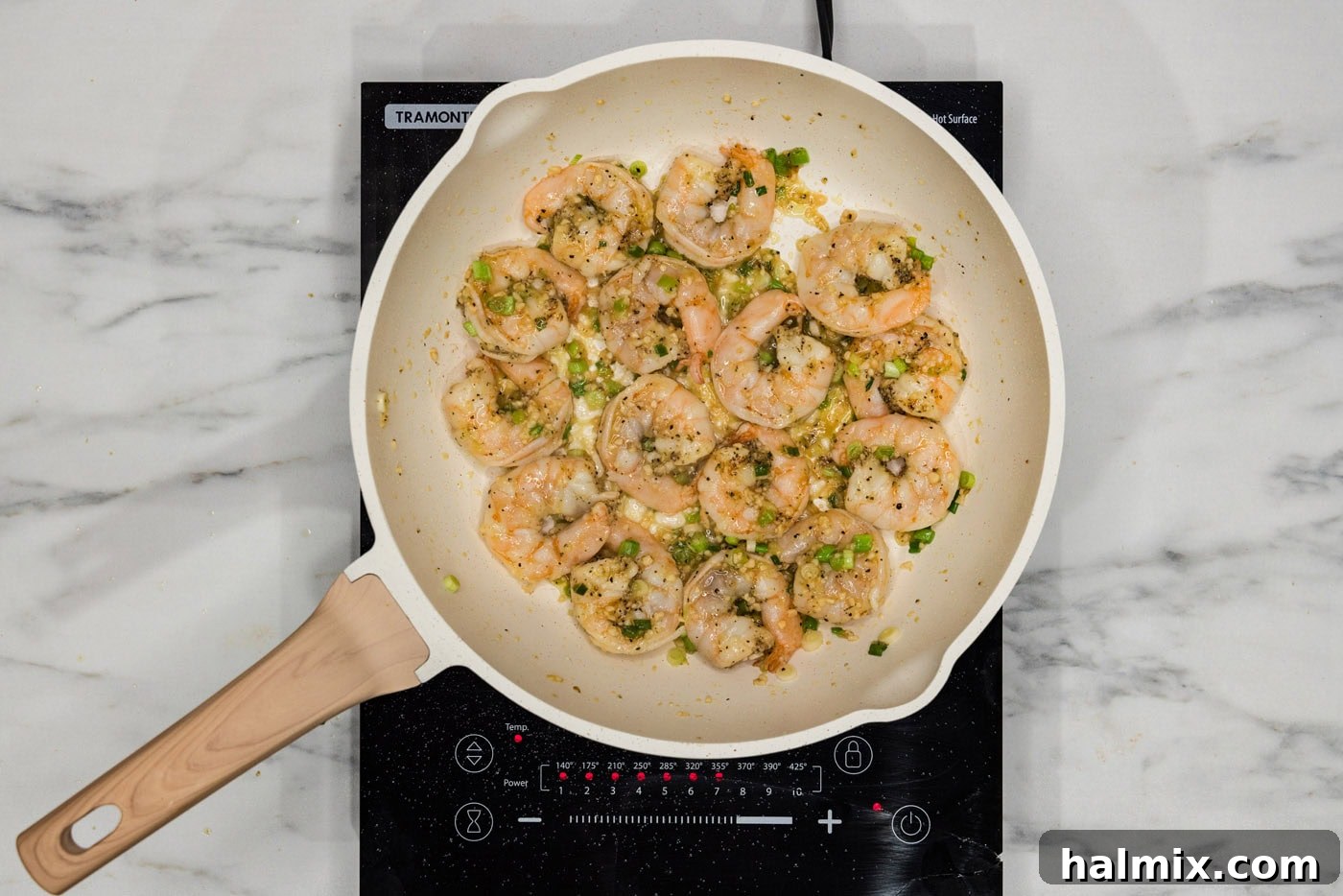 pink cooked shrimp in skillet with green onions