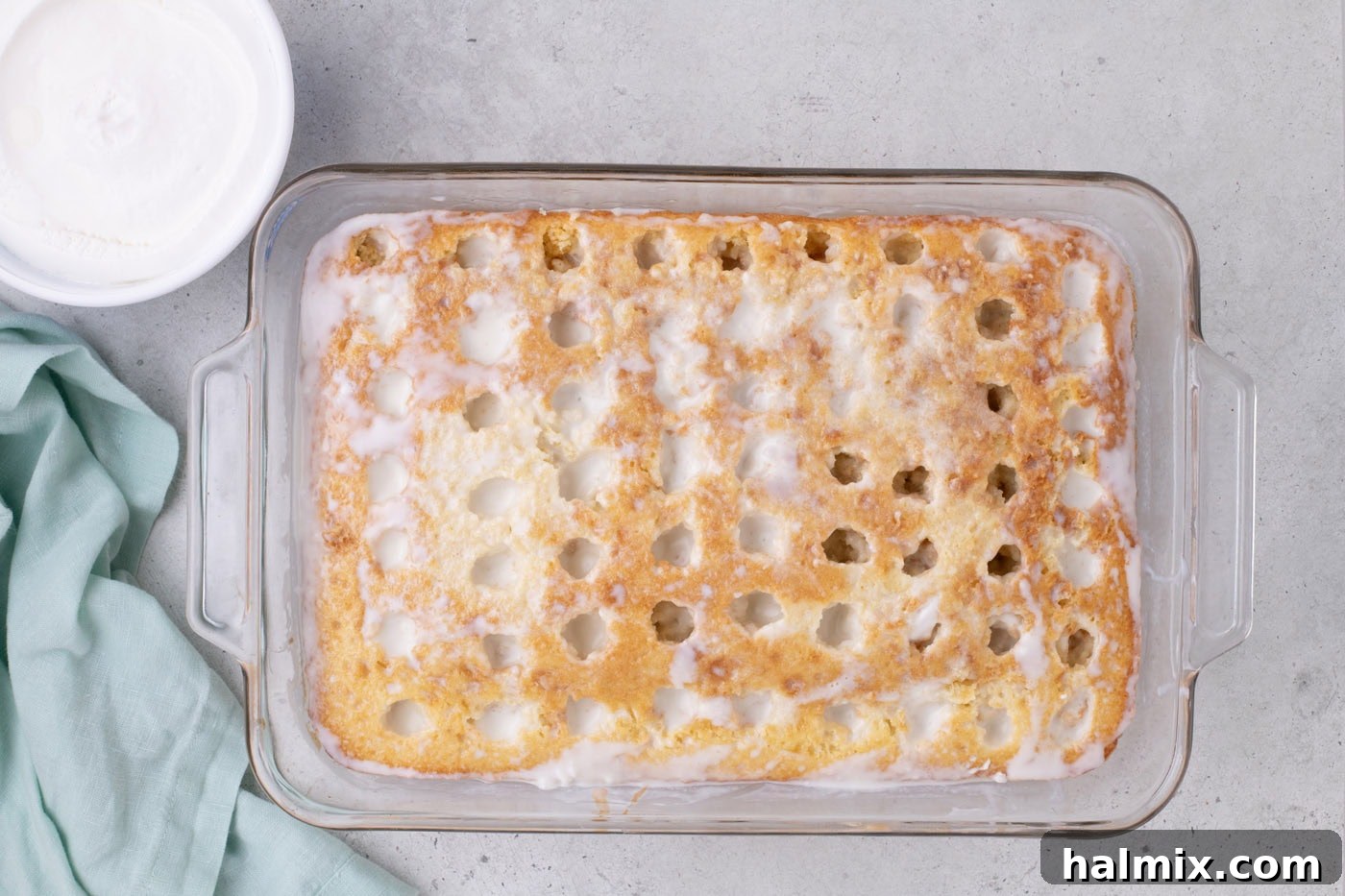 coconut cream filling poured over holes in a cake
