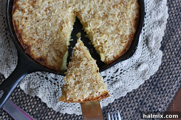 Easy Garden Cake 3 An overhead view of a whole lazy daisy cake in a cast iron skillet, with one slice being removed to reveal its moist interior.