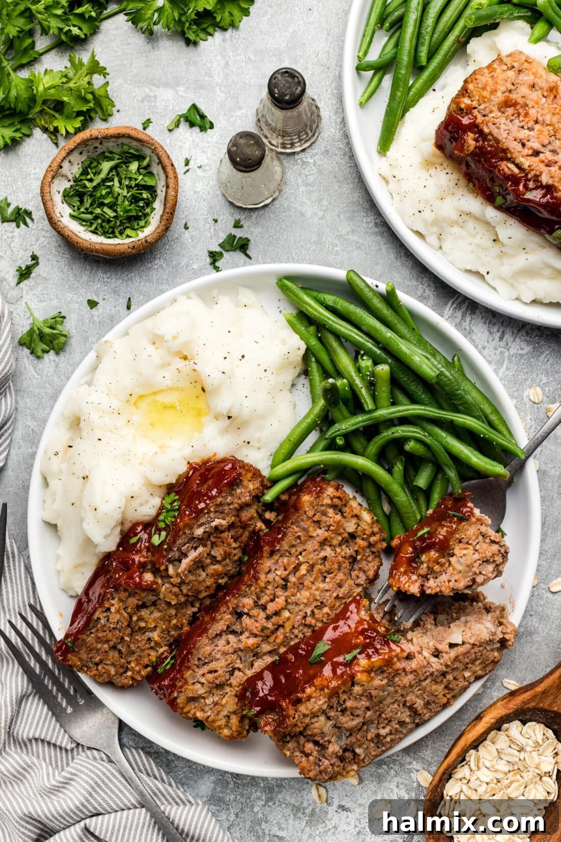 Slices of Quaker Oats Meatloaf beautifully plated alongside fluffy mashed potatoes and vibrant green beans.