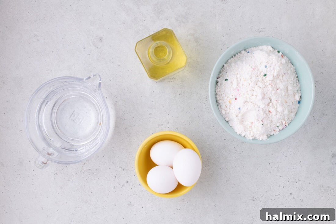 A flat lay photo showing the simple ingredients needed for Cake Mix Waffles: a box of cake mix, eggs, water, and vegetable oil.