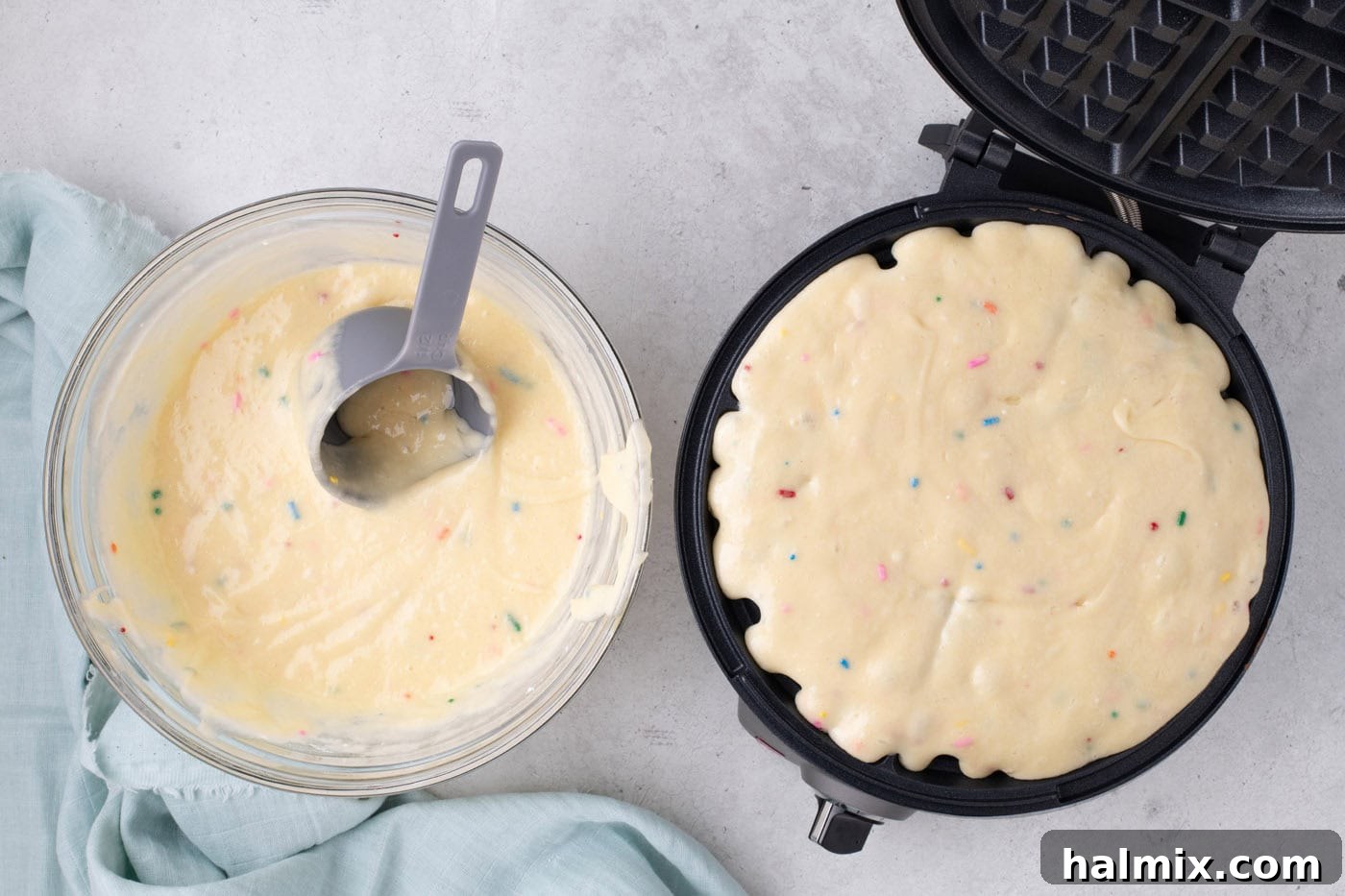 Cake mix batter being poured into a waffle iron.